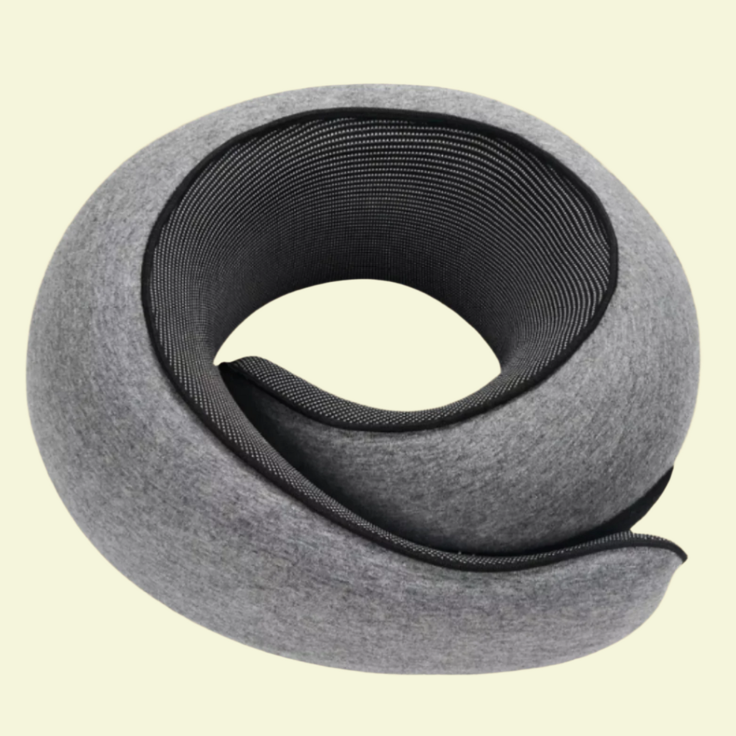 A rolled-up memory foam neck support pillow with a gray cover, coiled in a spiral shape.